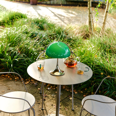 Louis Poulsen Panthella 250 portable lamp in green on an outdoor table with tea cups and teapot