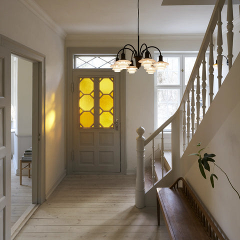 Louis Poulsen PH 1/1 Chandelier hanging in a bright Danish entry hall with painted staircase, light wood floors, and stained glass front door
