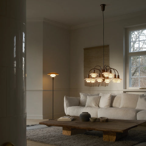 Louis Poulsen PH 1/1 Chandelier casting warm ambient light over a neutral linen sofa and live-edge coffee table in a softly lit Scandinavian living room