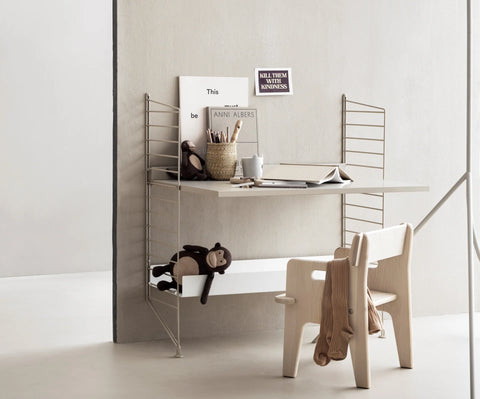 String Furniture Work Desk in beige finish from modular shelving system, styled as a Scandinavian kids desk with wooden chair and toys.