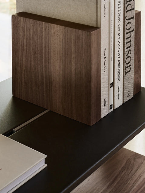 String Furniture Pira Bookend in walnut dividing books on a black steel shelf, detail