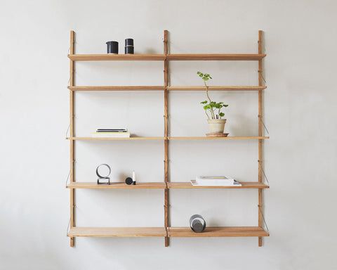 Frama Shelf Library Double Section in Natural Oak, oak shelving on a white wall with a potted seedling, books, a bowl and small objects