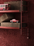 String® Pocket Metal shelf in red, styled with miniatures, Scandinavian modular shelving system.