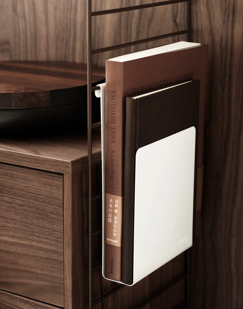 White String® Magazine Holder mounted on walnut shelving holding two design books