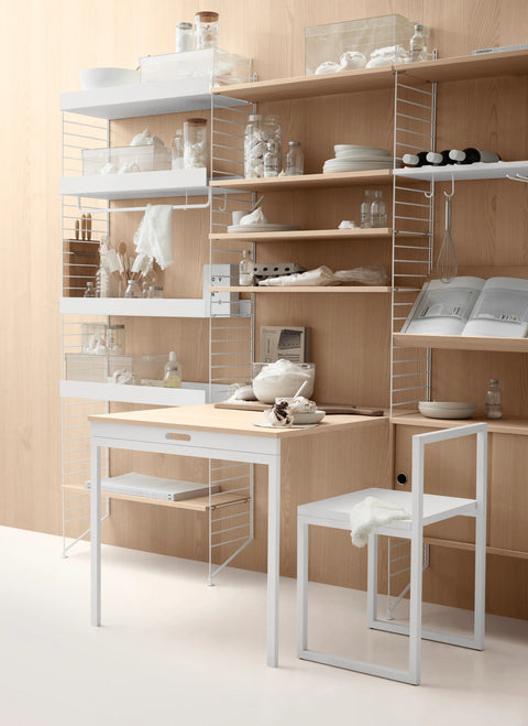 Oak String® folding table with white shelving in Scandinavian kitchen setup