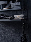 Close-up of dark blue String® Pocket shelf against textured wall with nautical rope and decorative objects