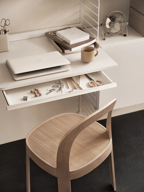 String Furniture Work Desk in white finish with pull-out drawer, part of the Scandinavian modular shelving system, styled with laptop and accessories.