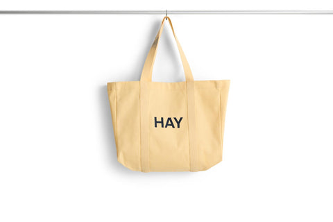 HAY Shopper Bag, Soft Yellow, cotton tote bag, pale yellow shopper hanging from a rail against a plain white background
