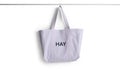 HAY Shopper Bag, Lavender, cotton tote bag, pale lilac shopper hanging from a rail against a plain white background