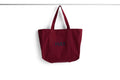 HAY Shopper Bag, Burgundy, cotton tote bag, deep red shopper hanging from a rail against a plain white background