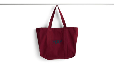 HAY Shopper Bag, Burgundy, cotton tote bag, deep red shopper hanging from a rail against a plain white background