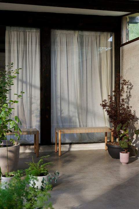 Betty TK4 Bench by &Tradition in oak with natural linen webbing styled in a sunlit modern entryway with plants