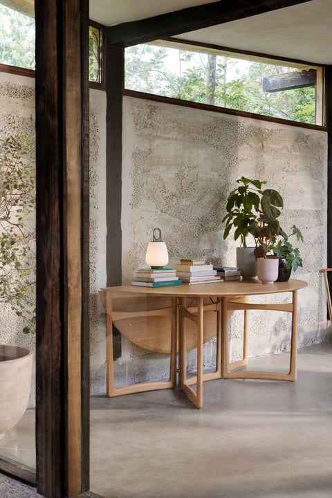 Drop Leaf HM6 table in oak by &Tradition styled as side table with books and plants in modern home