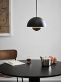 Flowerpot VP1 Pendant Light by &Tradition in Matt Black hanging over a black round dining table with a Pavilion AV1 chair.
