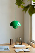 Flowerpot VP1 Pendant Light by &Tradition in Signal Green illuminating a wooden dining table with Collect Candleholder and Crafted Glass Vase.