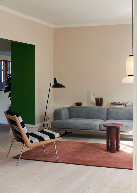 Tripod HM8 Floor Lamp by &Tradition in black, styled beside grey sofa and striped lounge chair in modern Scandinavian living room