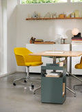 Rotate SC73 in hunter green by &Tradition beside dining table with yellow Rely chairs
