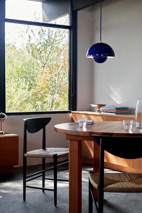 Dining room setting featuring the Flowerpot VP1 Pendant Light by &Tradition in Cobalt Blue above a round wood table and Drawn HM3 chairs.