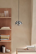 Flowerpot VP1 Pendant Light by &Tradition in Black and White Pattern hanging above a console with books and glass decor.