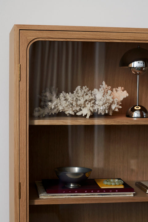 Detail of Trace SC88 Cabinet by &Tradition in Oak with glass doors displaying decor objects and Flowerpot VP9 Table Lamp