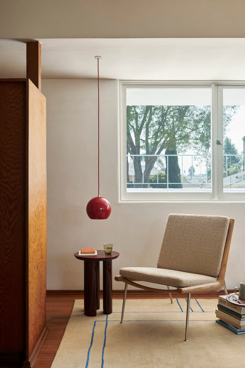 Boomerang HM1 Chair by &Tradition, designed by Hvidt & Mølgaard, upholstered in neutral boucle fabric with a modern pendant light above