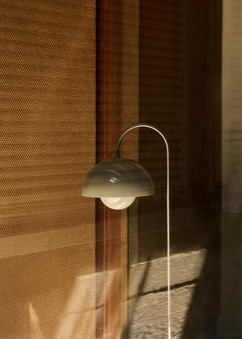 &Tradition Flowerpot VP12 Floor Lamp in Grey Beige casting a soft glow through wooden interiors overlooking a lake view.