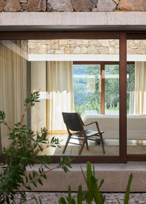 AX HM11 Lounge Chair by &Tradition in oak and walnut with sunlight streaming through concrete interior wall