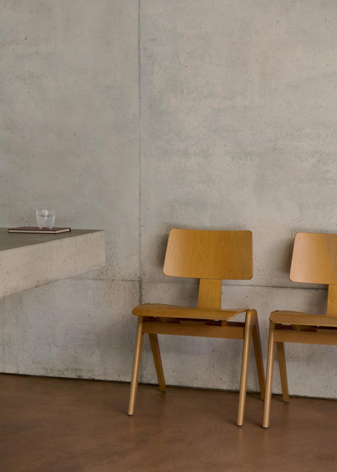 Daystak RD1 Side Chairs by &Tradition in beech placed against concrete wall in modern dining space