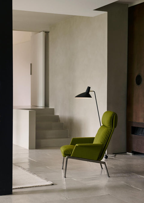 Tripod HM8 Floor Lamp by &Tradition paired with green upholstered lounge chair in minimalist modern home interior