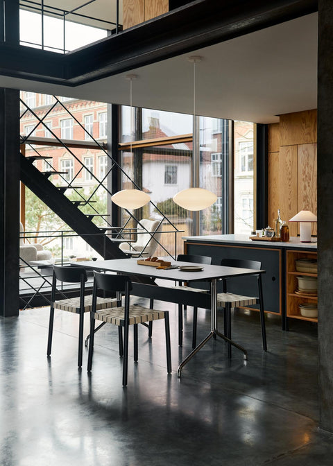 Contemporary dining space with Betty TK1 Side Chairs by &Tradition in black oak around dark dining table with large windows