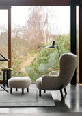Tripod HM8 Floor Lamp by &Tradition next to lounge chair and ottoman with large window backdrop, Scandinavian modern interior