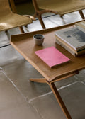 Close-up of X HM13 Coffee Table by &Tradition in oak with books and coffee cup, modern Danish furniture design