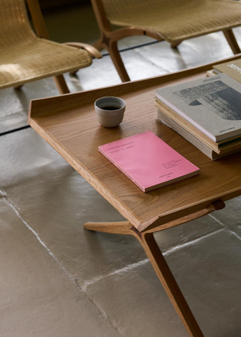 Close-up of X HM13 Coffee Table by &Tradition in oak with books and coffee cup, modern Danish furniture design