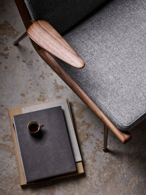 Close-up detail of &Tradition Boomerang HM2 Lounge Chair by Hvidt & Mølgaard with grey upholstery and walnut armrest