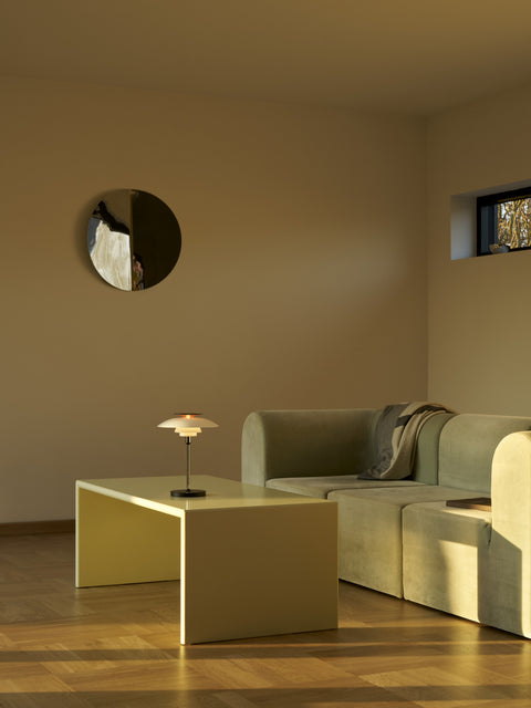PH 80 Portable Lamp in chrome softly glowing on a coffee table in a modern living room interior