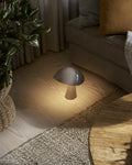 Louis Poulsen Rumee 220 Portable Lamp in Earth Grey illuminating a cozy living room corner.