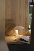 Rumee 220 Portable Lamp in Cloud White placed on a wooden counter beside a cutting board and lemons.