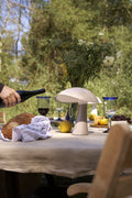 Rumee 220 Portable Lamp in Earth Grey illuminating an outdoor dining table with bread, wine, and flowers.