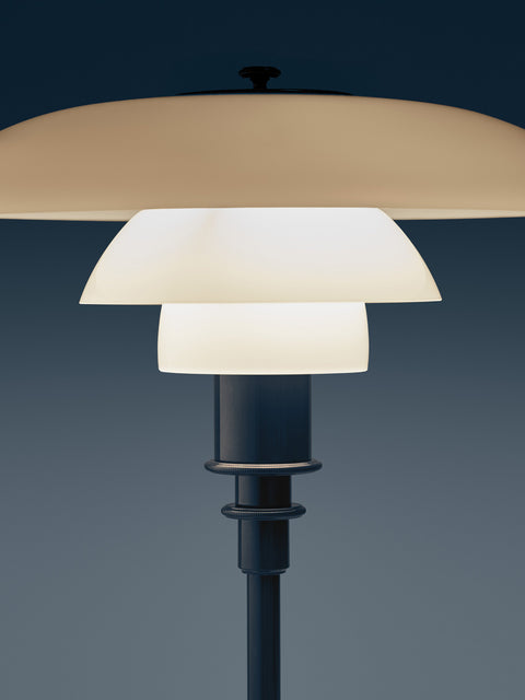 Close-up of the lit Louis Poulsen PH 2/1 Table Lamp in Glossy Deep Blue against a slate blue background