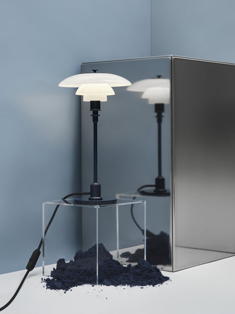 Two Louis Poulsen PH 2/1 Table Lamps in Glossy Deep Blue, lit on an acrylic plinth against a pale blue backdrop with a steel sheet