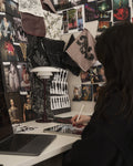 Louis Poulsen PH 2/1 Table Lamp in Glossy Burgundy on a studio desk as a designer sketches, against a collaged mood-board wall