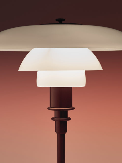 Close-up of the lit Louis Poulsen PH 2/1 Table Lamp in Glossy Burgundy, showing the stepped opal shades and ringed stem collar