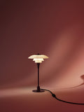 Louis Poulsen PH 2/1 Table Lamp in Glossy Burgundy, lit against a deep red draped backdrop