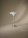 Louis Poulsen PH 3/2 Glass Table Lamp in Glossy Beige, unlit against a soft taupe draped backdrop with a white cord