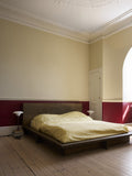 Louis Poulsen PH 3/2 Glass Table Lamps in Glossy Burgundy and Glossy Beige, lit either side of a low bed in a bedroom with a deep red painted dado