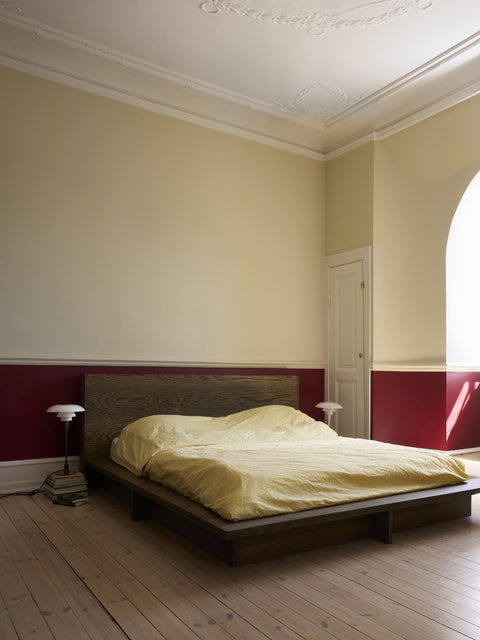 Louis Poulsen PH 3/2 Glass Table Lamps in Glossy Burgundy and Glossy Beige, lit either side of a low bed in a bedroom with a deep red painted dado