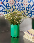 HAY Arcs Vase, Small, Green, green metal flower vase with scalloped sides, with white blossom on a dark counter below blue patterned tiles