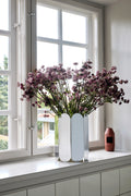 HAY Arcs Vase, Large, Mirror, mirror finish steel vase, filled with purple dried flowers on a windowsill beside a small copper bottle vase