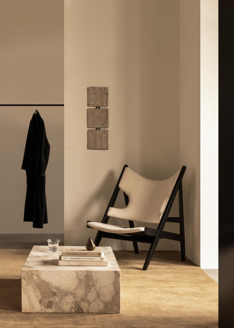 Knitting Lounge Chair in cream upholstery with black oak frame by Audo Copenhagen, styled beside a marble coffee table.