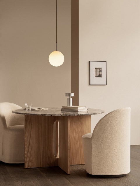 Audo Copenhagen Tearoom Swivel Chair, With Loose Cover, cream Tearoom Club Chairs at the Androgyne Dining Table. A TR Bulb Pendant hangs above the grey marble tabletop